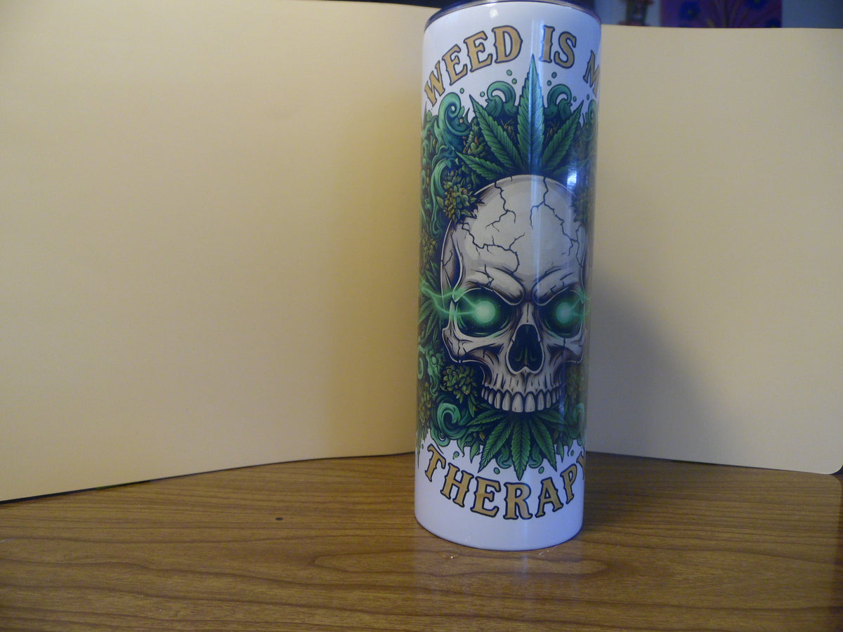 Weed Is My Therapy 20 oz skinny tumbler with glowing-eyed skull, green cannabis leaves and gold banner lettering