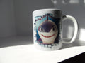 Front view of white ceramic mug with smiling orca artwork and printed broken-wall effect